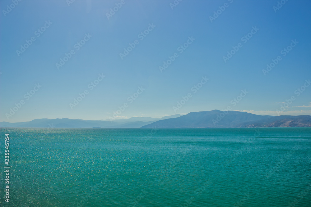 abstract wallpaper landscape of mountain ridge horizon silhouette and sea calm water surface in clear morning foggy weather time, copy space abstract wallpaper landscape of mountain ridge horizon silhouette and sea calm water surface in clear morning foggy weather time, copy space