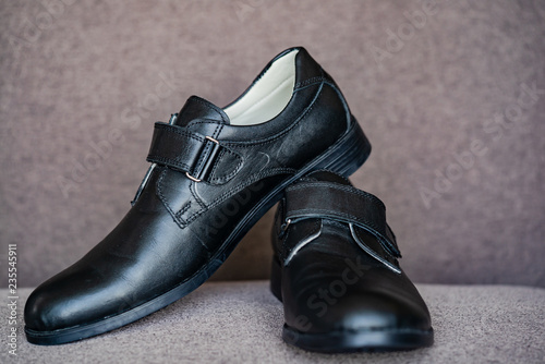 Black leather shoes for boy. Classic boys children's new black school shoes on grey background.