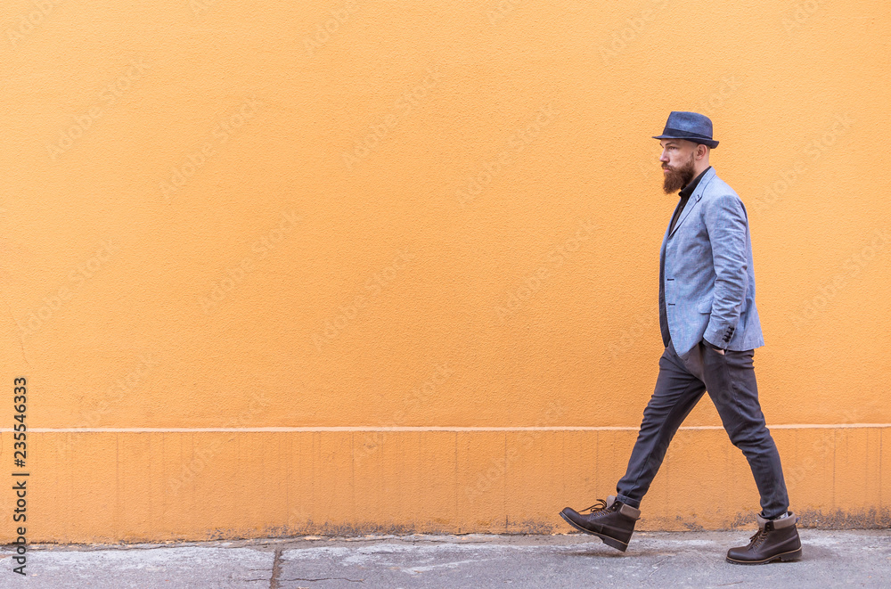 stylish man with a beard and a hat near the desirable wall stylish man with a beard and a hat near the desirable wall