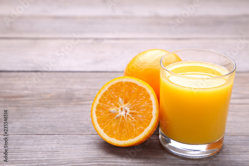 Glass of orange juice with orange on wooden table