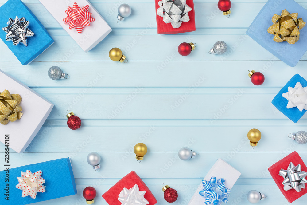 In the center of a blue background Copy space. In a circle are red, gold and silver Christmas balls, gift boxes with bows. Festive layout. In the center of a blue background Copy space. In a circle are red, gold and silver Christmas balls, gift boxes with bows. Festive layout.