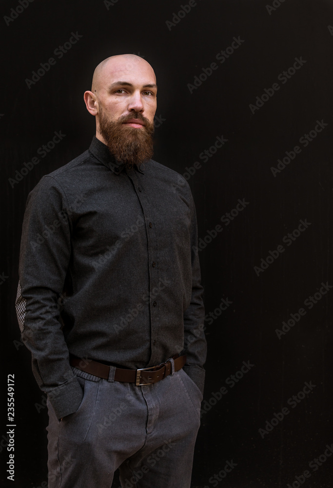 bald man with a beard in a black shirt on a dark background bald man with a beard in a black shirt on a dark background