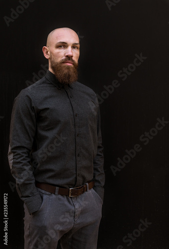 bald man with a beard in a black shirt on a dark background