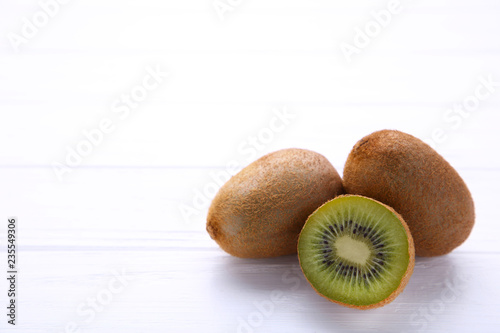 Fresh kiwi fruit and half of kiwi on white wooden background