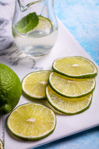 Sliced lime and juice on ceramic platter closeup © Yingko