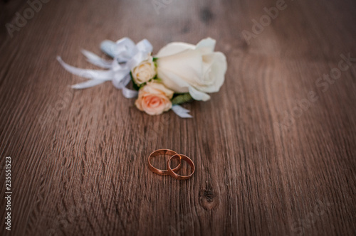 white flowers and wedding rings on wooden background