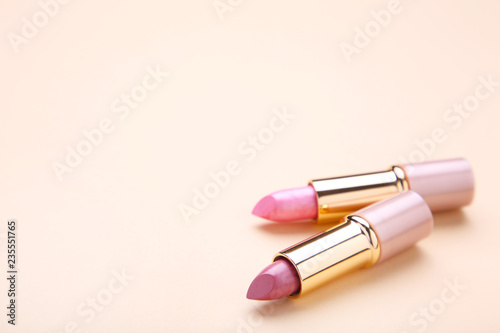 Two lipsticks on beige background, close up