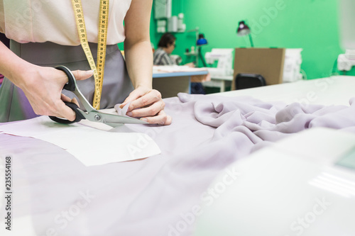 Sewing workshop. Seamstress at work. Marking and cutting fabric.