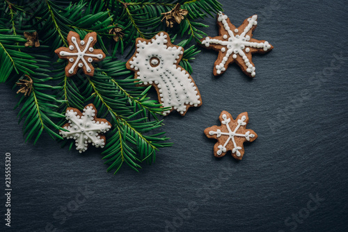 Frame with fir branches, Gingerbread cookies and Christmas decorations on dark wooden background. Top view.