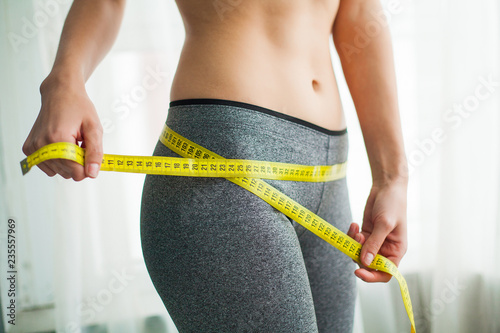 Фотография Hands measuring waist with a tape