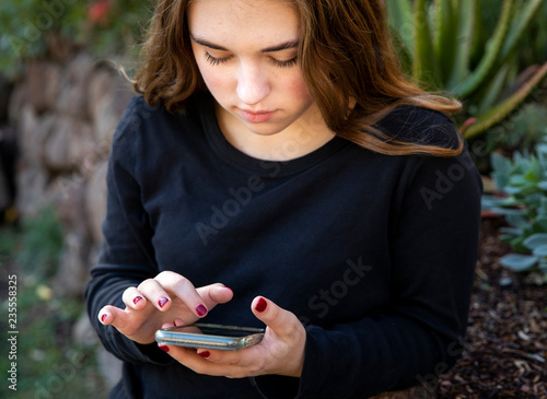 Teenage girl holding smart phone outdoors