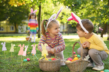 Cute little children hunting eggs in park. Easter tradition