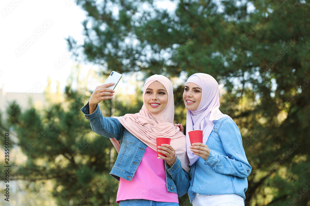 Fototapeta premium Muslim women in hijabs taking selfie outdoors