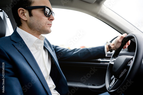 man in suit sits behind the wheel of a car © pantovich