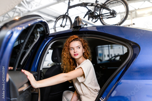 Red-haired girl sitting in a car with bicycles on the roof