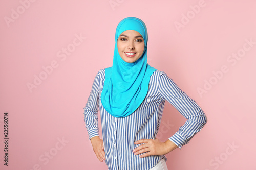 Portrait of young Muslim woman in hijab against color background