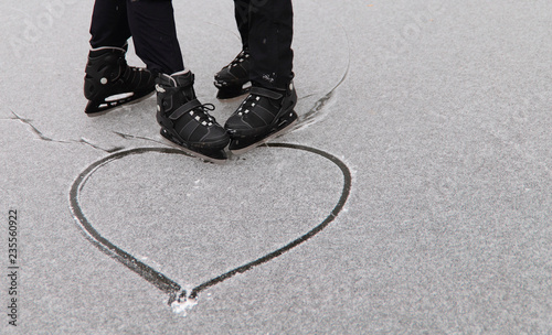 Gay couple skating drew a heart in the snow. The concept of same-sex relationships. Cropped shot, space for text.