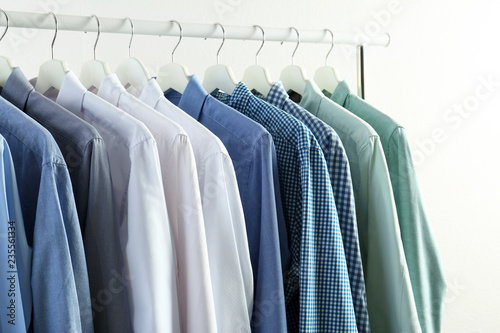 Men's clothes hanging on wardrobe rack against white background