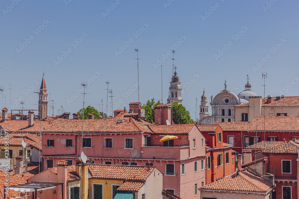 Terracotta rooftops of venetian houses under blue sky in Venice, Italy
