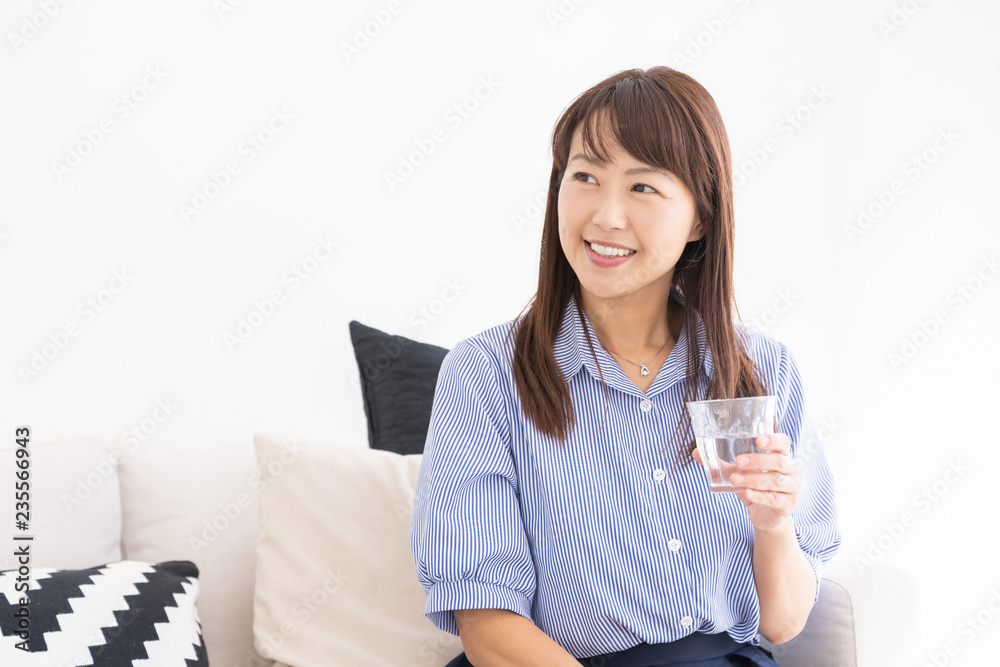 部屋で水を飲むミドル女性 部屋で水を飲むミドル女性
