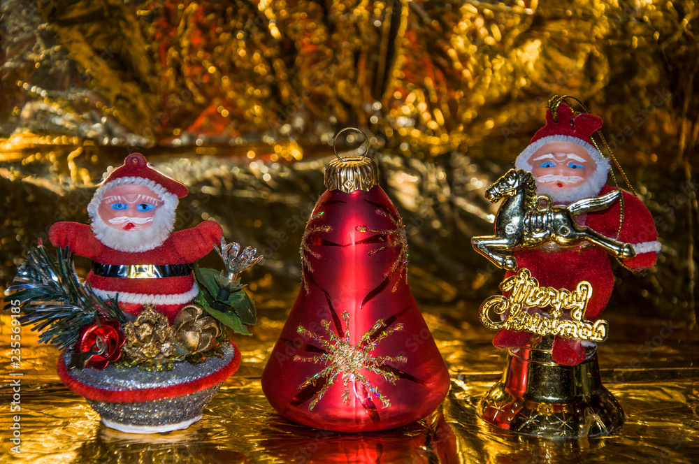Two Santa Claus and a Christmas bell, on a gold background.