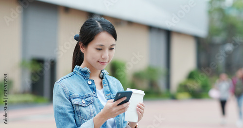 Woman use of smart phone and holding coffee cup