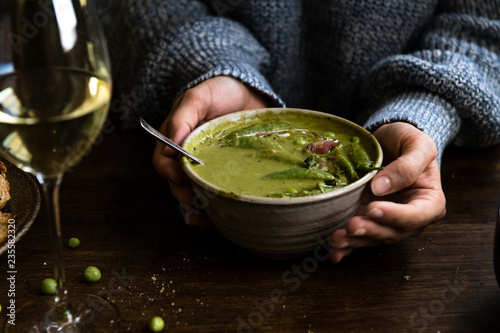 Woman holding a bowl of green pea soup