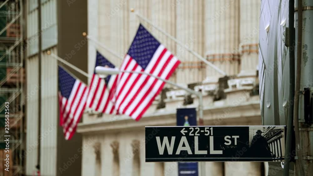 Wall Street road sign and New York Stock Exchange out of focus in downtown Manhattan.