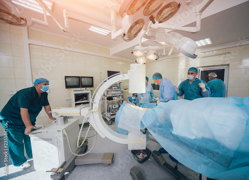 Process of trauma surgery operation. Group of surgeons in operating room with surgery x-ray equipment.