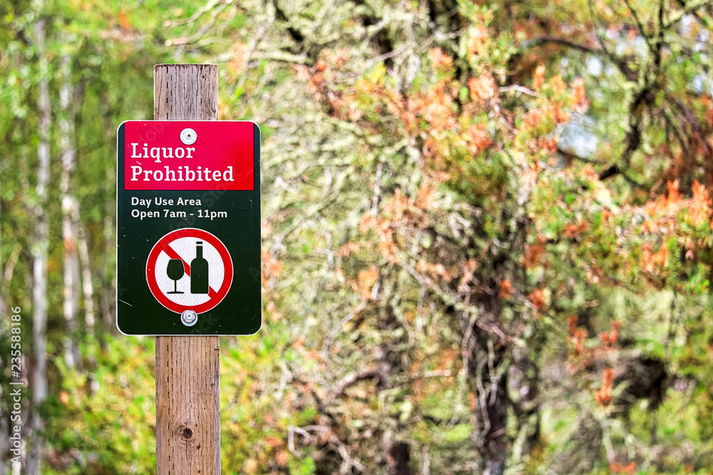 A liquor prohibited day use sign with trees in the background A liquor prohibited day use sign with trees in the background