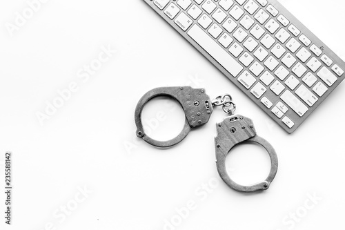 Cyberfraud concept. Handcuff near keyboard on white background top view space for text photo