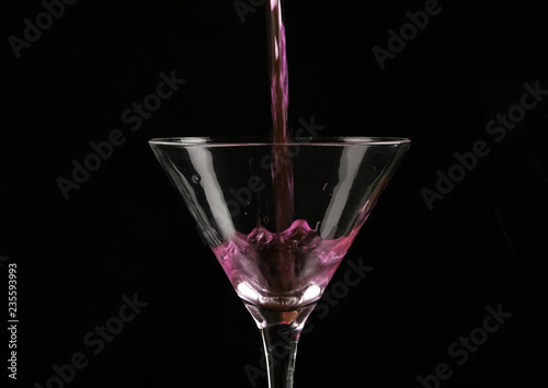 pink cocktail poured into a glass on a dark background.