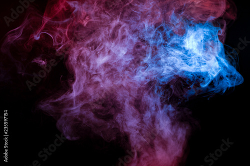A background of blue, red and violet wavy smoke in the shape of a ghost's head or a man of mystical appearance on a black isolated ground. Bright abstract pattern of steam from vape.