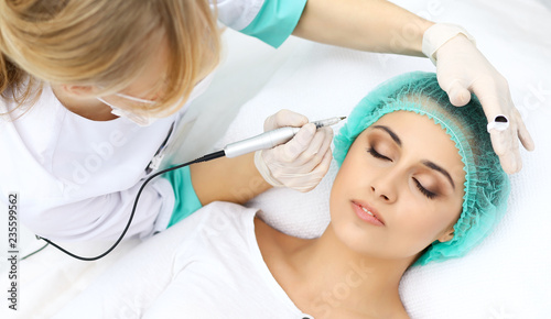 Professional beautician doing eyebrow tattoo at woman face. Permanent brow makeup in beauty salon  closeup.  Cosmetology treatment