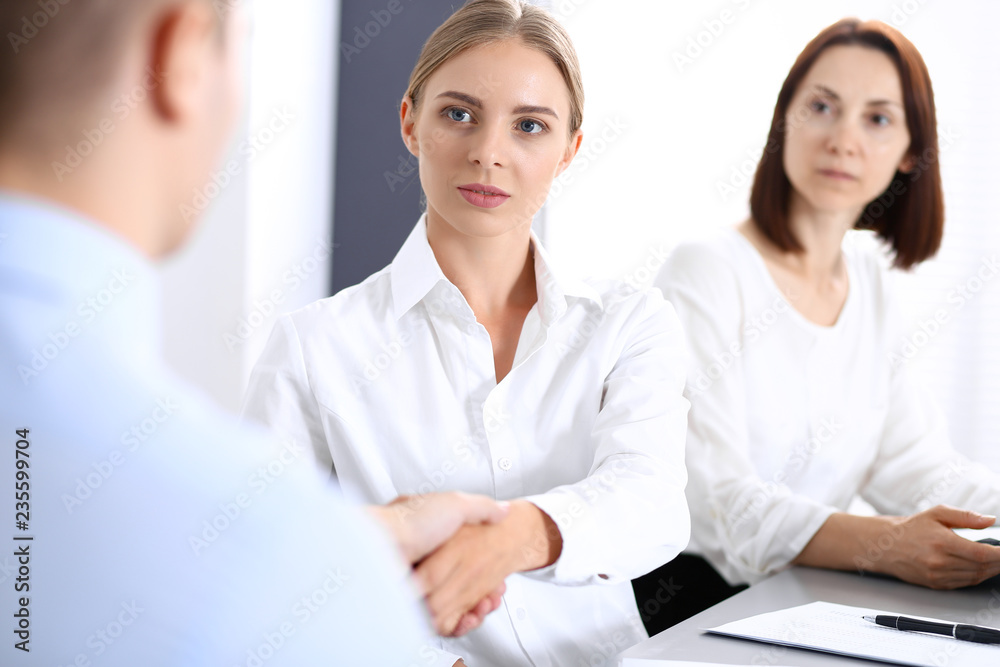 Business handshake by blonde woman and her partner at meeting. Concept of success and agreement Business handshake by blonde woman and her partner at meeting. Concept of success and agreement