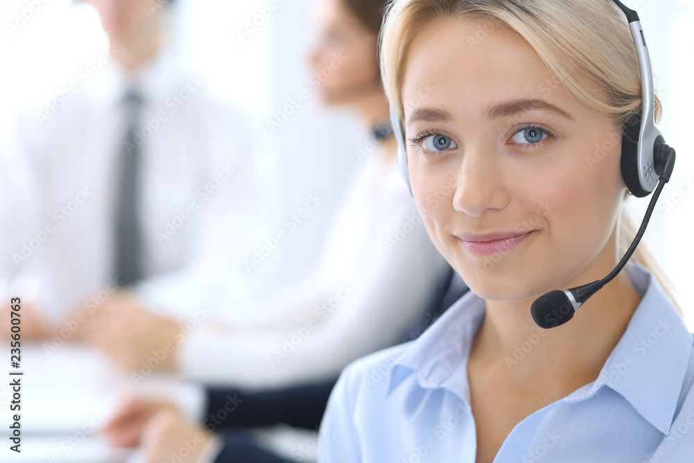Call center. Group of operators at work. Focus at blonde business woman in headset Call center. Group of operators at work. Focus at blonde business woman in headset