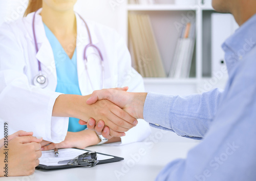 Doctor and patient shaking hands. Family couple at medical exam, just hands at the table. Medicine concept