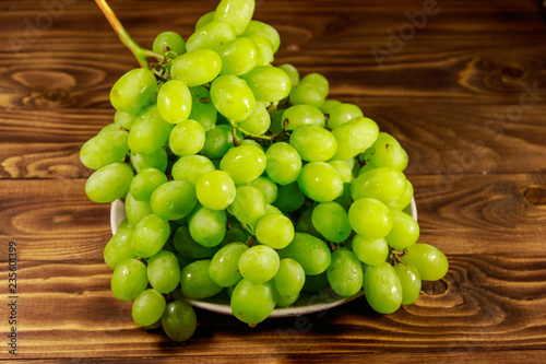Tasty fresh white grape in a plate on wooden table