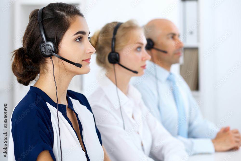 Call center operators at work. Focus at beautiful latin american woman in headset Call center operators at work. Focus at beautiful latin american woman in headset
