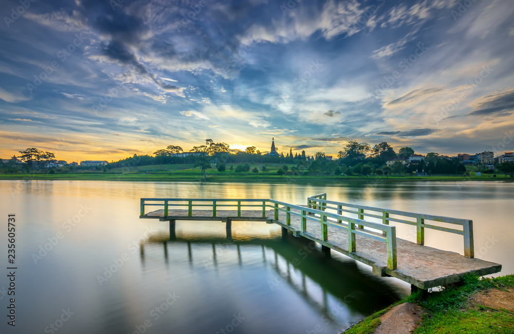 Obraz premium Sunrise on the small bridge overlooking the lake with the dramatic sky welcomes new day in the tourist city of Vietnam