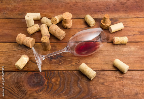 Glass with wine lying on its side among of corks
