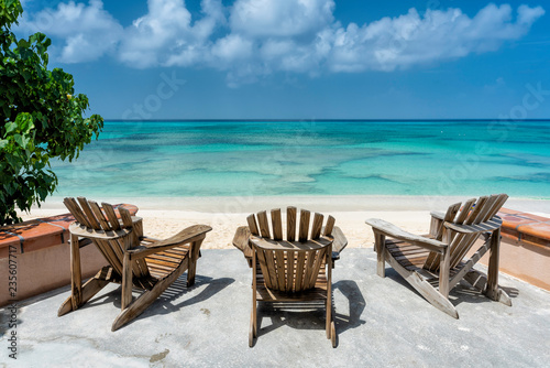 Wooden beach chairs facing the clear tropical ocean