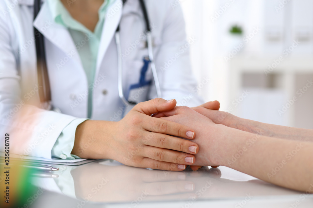 Hand of a doctor woman reassuring to female patient, close-up. Medical ethics and trust concept Hand of a doctor woman reassuring to female patient, close-up. Medical ethics and trust concept
