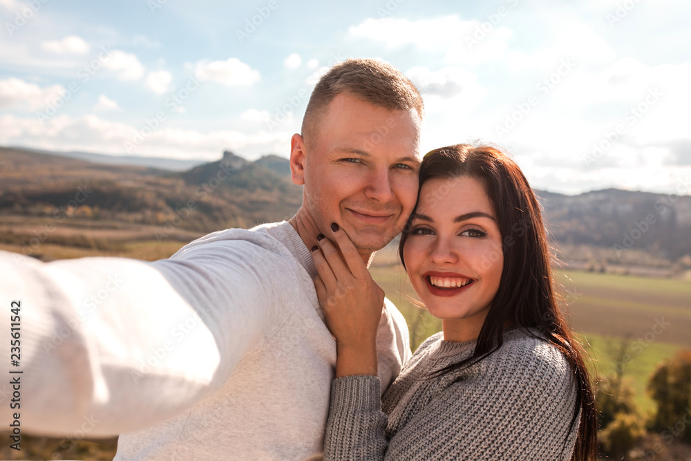 Happy couple making selfie against the mountains.