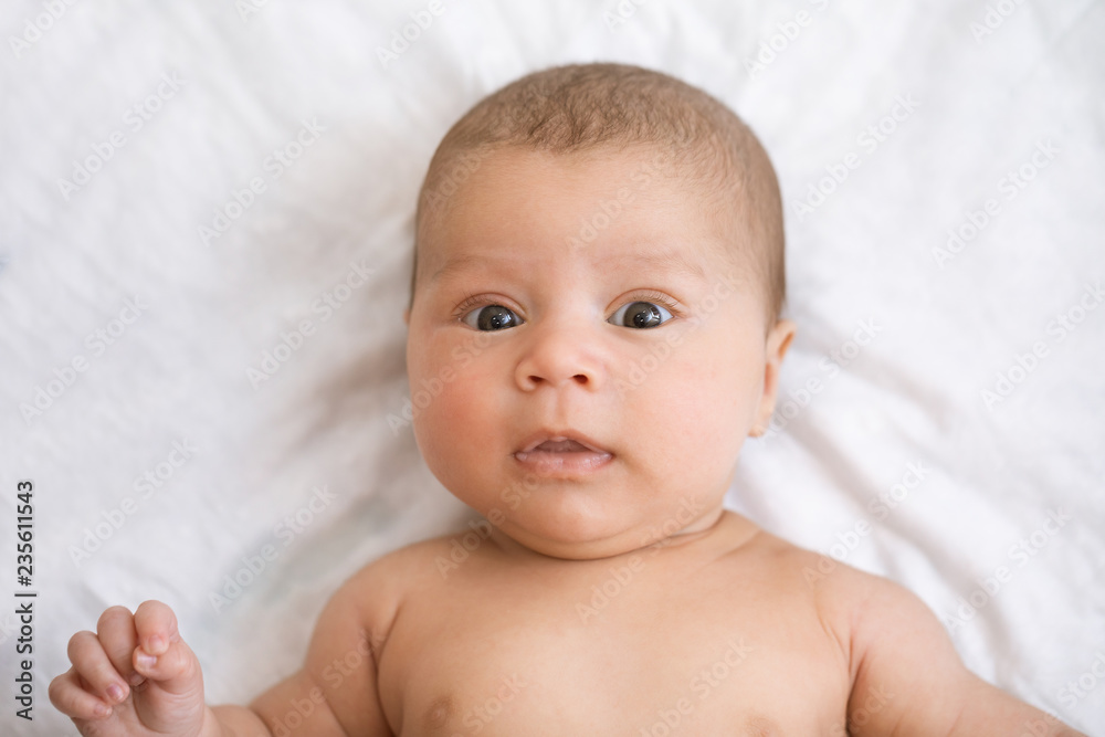 Close-up portrait of baby awake. Newborn baby lies on his back and tries to smile for the first time Close-up portrait of baby awake. Newborn baby lies on his back and tries to smile for the first time