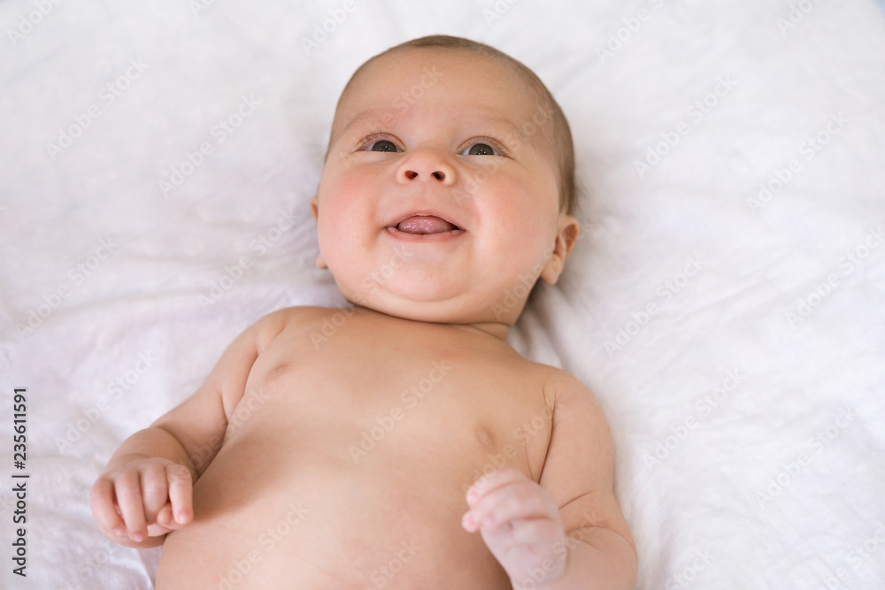 Close-up portrait of baby awake. Newborn baby lies on his back and tries to smile for the first time Close-up portrait of baby awake. Newborn baby lies on his back and tries to smile for the first time