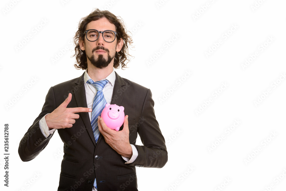 Handsome Caucasian businessman holding piggy bank and pointing f Handsome Caucasian businessman holding piggy bank and pointing f