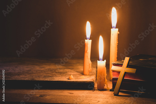 Cross with bible and candle on a old oak wooden table. Beautiful gold background. Religion concept. photo