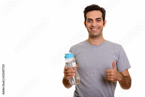Young happy Persian man holding water bottle and giving thumb up
