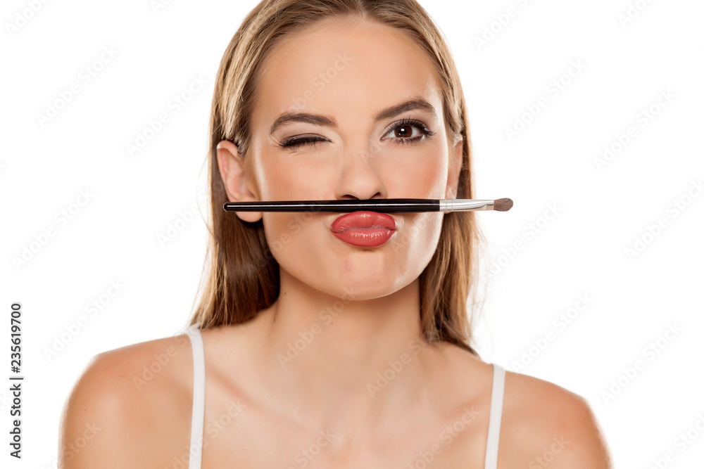 young beautiful girl posing with makeup brush on white backgeound young beautiful girl posing with makeup brush on white backgeound